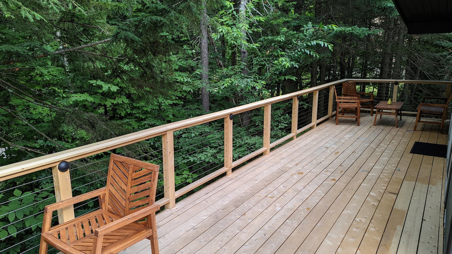 Wrap-around cedar deck with wood chairs tucked among the trees
