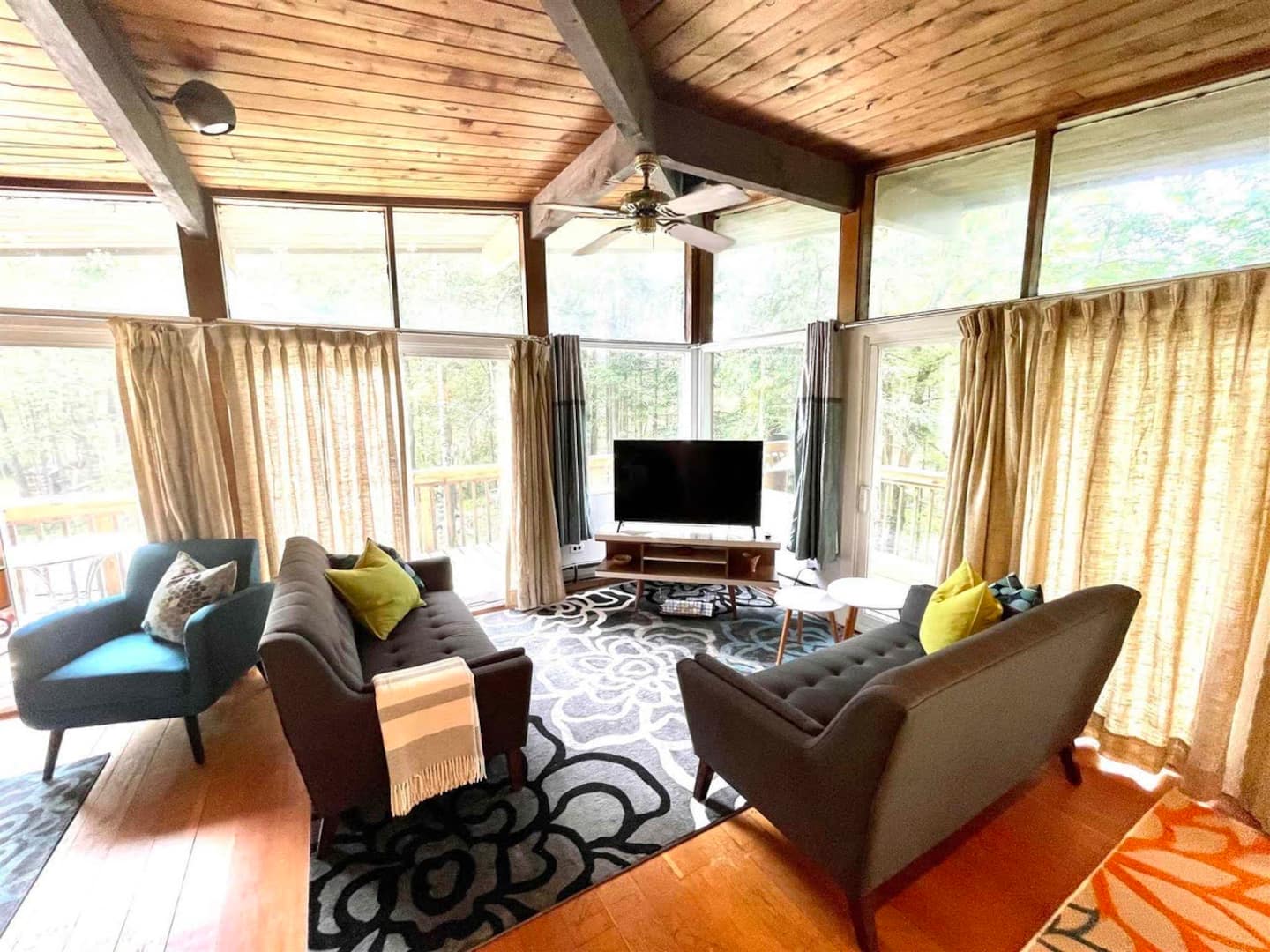Living room with pine cathedral ceiling, walls of windows, and views of the woods