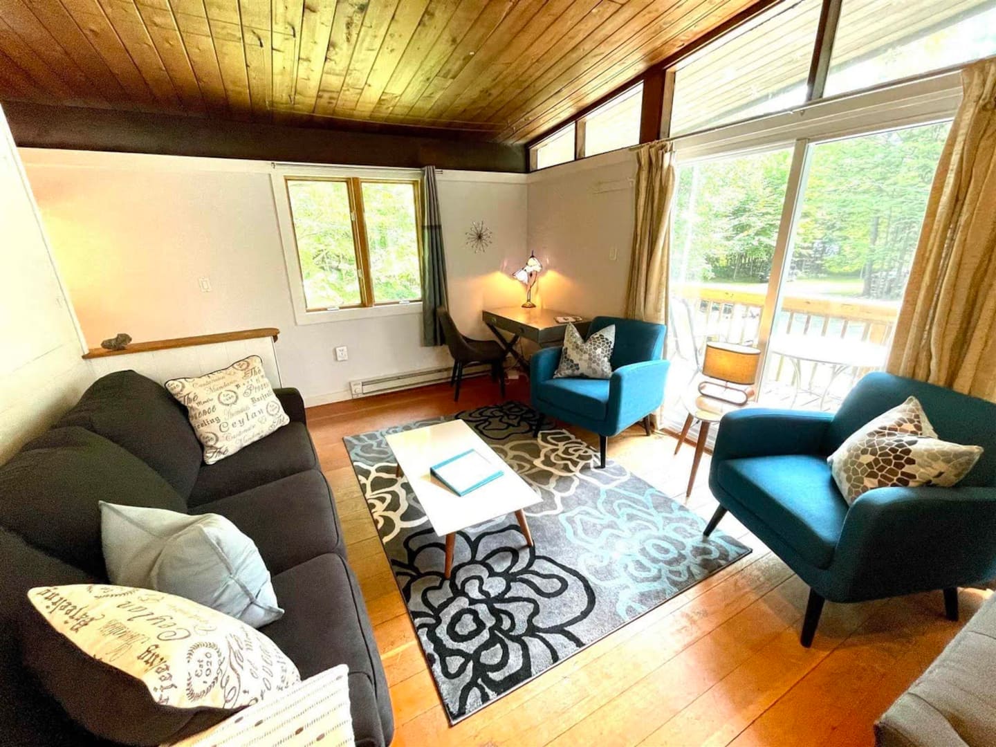 Bright sitting area with blue armchairs, a sofa, and sliding doors to the deck
